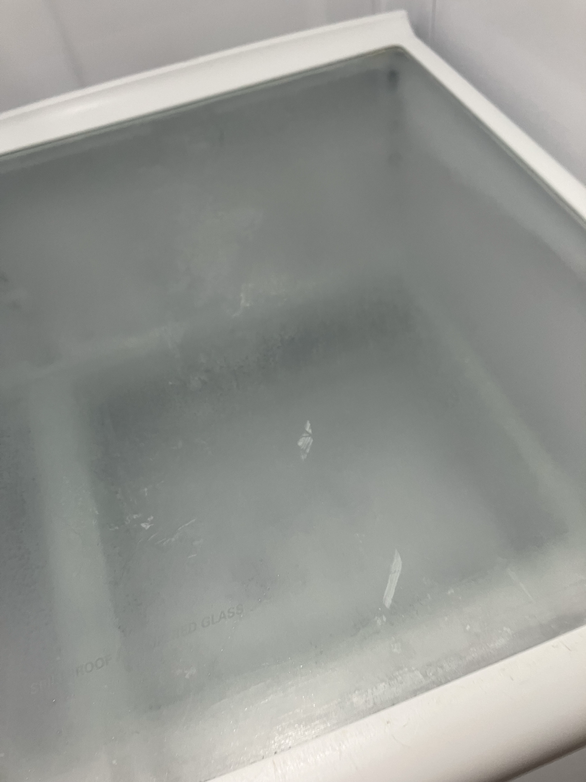 Film and marks visible on a refrigerator glass shelf under close inspection
