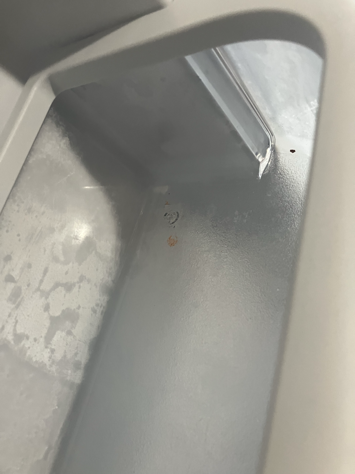 Residue and small marks visible around a refrigerator shelf or drawer area